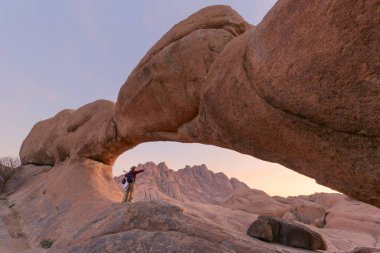 Spitzkoppe bölgesinde genç bir çift. Damaraland Namibya 'da taş kemerleri ve eşsiz kaya oluşumları var.