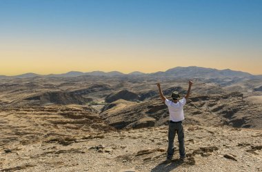 Erkek turist gün batımında gri dağın tepesinde