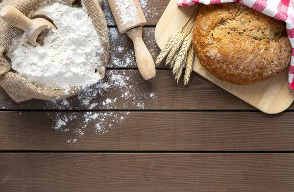 bread on cutting board, flour and rolling pin on wooden background, copy space