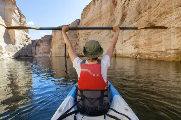 Colorado Nehri 'nde Kano kürek çeken maceraperest bir kadın. Glen Canyon, Arizona, Amerika Birleşik Devletleri. Amerikan Dağları Doğa Manzarası Arkaplanı. Macera Yolculuğu
