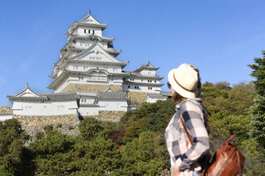 Şapkalı genç bayan turist Himeji kalesine bakıyor - seyahat konsepti