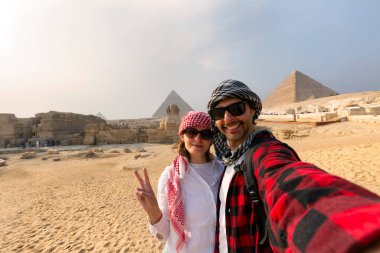 Genç bir çift, Mısır 'daki Giza Piramitleri' nin önünde selfie çekiyor.