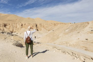 Krallar Vadisi 'ne bakan bir kadın turist. Firavunların mezarları. Evet. Tutankamon. Şatafatlı. Mısır. Antik mimari anıtı.