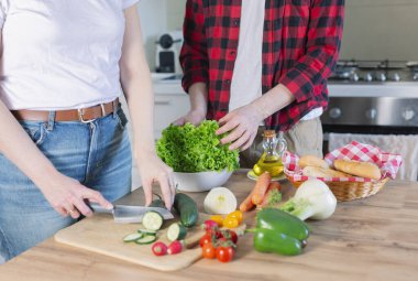 Genç çift evde sebze doğrayan bir yemek hazırlıyor, sağlıklı bir yaşam tarzı var..