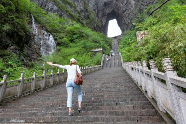Genç bayan turist, Tianmen Shan Ulusal Parkı 'nda sisli manzaranın tadını çıkarıyor.