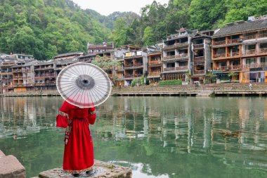 Çinli gezginler tuojiang nehri ve tarihi Xiangxi Antik Kenti veya Çin 'in Hunan kentindeki antik Fenghuang şehrinde fotoğraf çekmek için geleneksel kabile kıyafetleri kiralarlar.