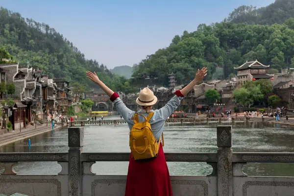 Feng Huang Antik Kasabası 'nın güzel manzarasına bakan genç bayan turist Hunan Eyaleti, Çin' deki ünlü turizm merkezi.