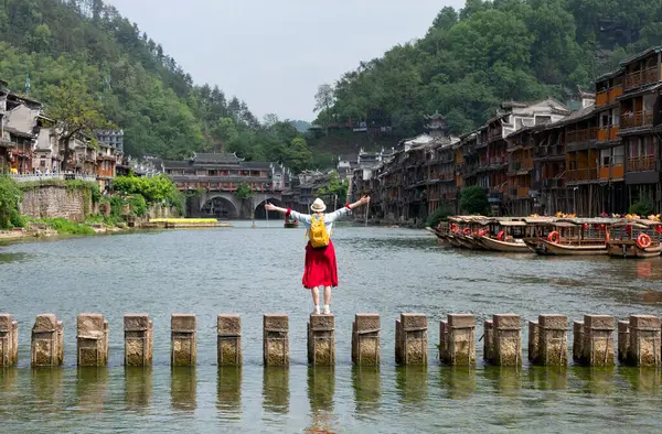 Tarihi Xiangxi Antik Kasabası 'ndaki Tuojiang Nehri' ni ya da Hunan, Çin 'deki Fenghuang Eski Kasabası' ndaki kırmızı elbiseli genç turist..