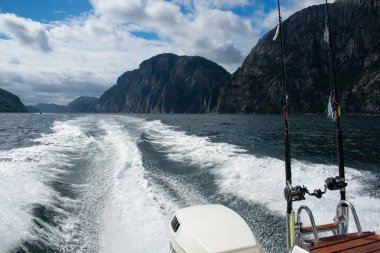 Boat with fish rods and gear with scenic mountains / fjords in the background - Norway 