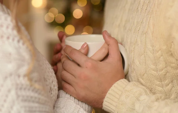 幸福的夫妻的手拿着暖灯的热杯作为背景 圣诞节的概念 — 图库照片