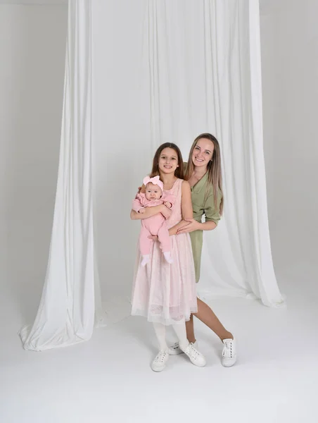 Mom with two daughters. Beautiful girls in a white room