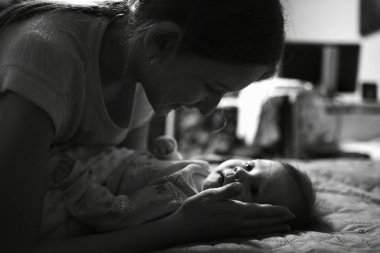 Genç annenin yatak odasındaki yeni doğmuş kızına bakarken, siyah ve beyaz.