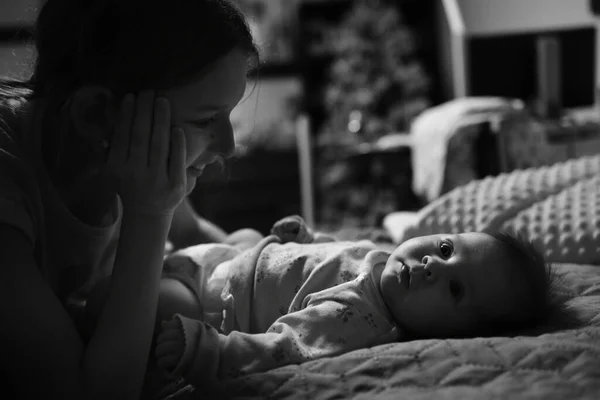 ベッドルームで黒と白の新生児の娘を見ている若い母親のクローズアップ — ストック写真