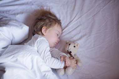 The baby is sleeping in bed. The child lies on a light blanket.