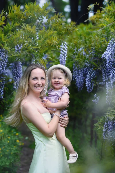 Frau Und Ihre Kleine Tochter Posieren Frühlingspark Mit Glyzinien Blumen — Stockfoto