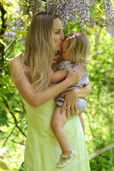 Frau Und Ihre Kleine Tochter Posieren Frühlingspark Mit Glyzinien Blumen — Stockfoto
