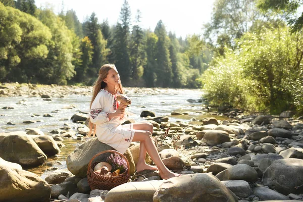 Młoda Kobieta Siedząca Molo Lesie Koszem Świeżych Kwiatów — Zdjęcie stockowe