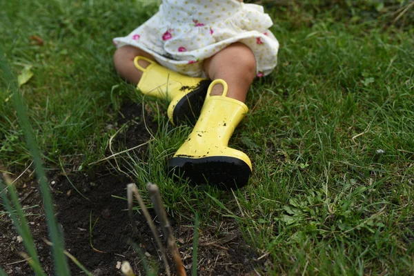 Żółte Gumowe Buty Stopach Dziecka Buty Ogrodzie Trawie Czarnej Ziemi — Zdjęcie stockowe