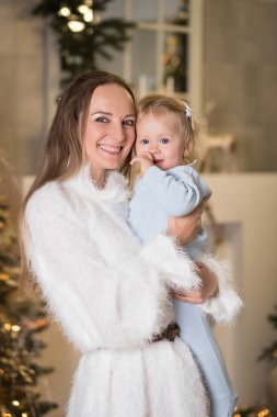 Anne ve kızı Noel ağacının yanında gülüp oynuyorlar.