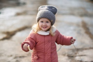 Küçük güzel bir kız parkta bir göletin yanında yürüyor. Küçük bir çocuk kuşları ve güvercinleri besler.