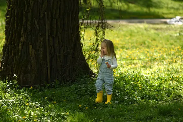 아름다운 소녀는 민들레 들판에서 걸어갑니다 아이의 노란색 부츠를 머리를 로열티 프리 스톡 이미지