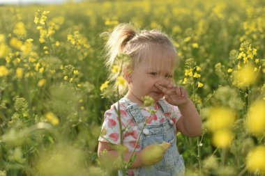 İki yaşında küçük bir kız, bir yakut tohumu tarlasında yürüyor. Tecavüze karşı alerji. Çocuk burnunu kaşıyor.
