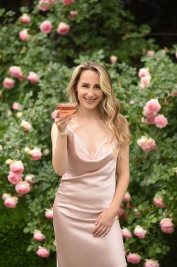 Çiçekli güzel bir genç kadının portresi. Uzun saçlı kız. Elinde bir bardak şarap olan bir kadın..