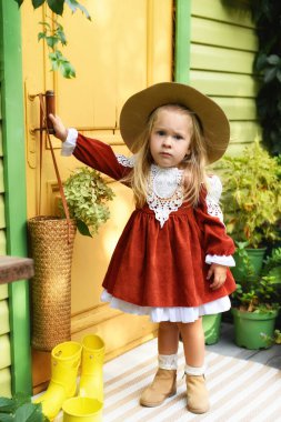 Güz bahçesinde oynayan iki yaşında güzel bir kız. Evin bahçesinde oynayan küçük bir çocuk. Elbiseli, uzun saçlı kız.