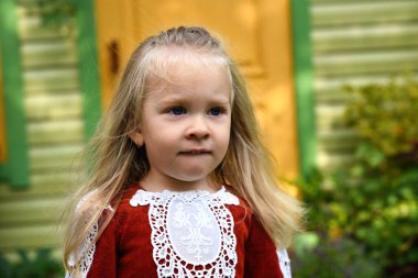 Güz bahçesinde oynayan iki yaşında güzel bir kız. Evin bahçesinde oynayan küçük bir çocuk. Elbiseli, uzun saçlı kız.