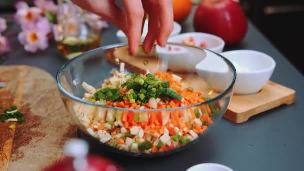 野菜サラダにチョップした緑の玉ねぎを加える女性 テーブルのクローズアップショット キッチンで料理する — ストック動画