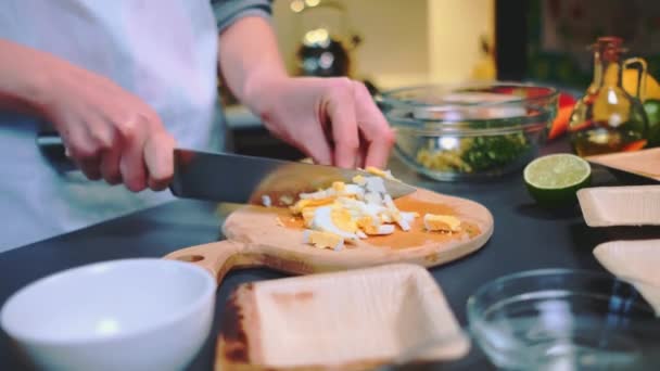 女性は切断板の小さな部分に卵をカットします テーブルのクローズアップショット キッチンで料理する — ストック動画