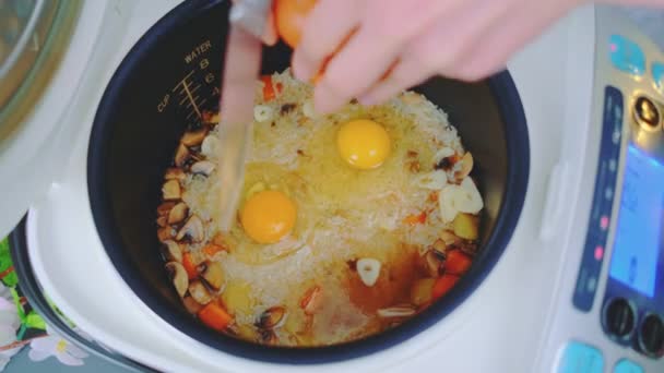 一个女人把鸡蛋和蔬菜一起放在米饭里 在慢锅里放蔬菜的米饭 厨房桌子的顶视图 厨房里的烹调 — 图库视频影像
