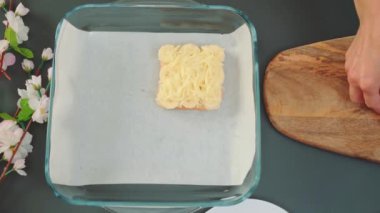 Kadın elleri kızarmış ekmek, muz ve tereyağlı sandviçi pişirme kabına koyar. Mutfak masasının üst manzarası. Mutfakta yemek pişirmek.