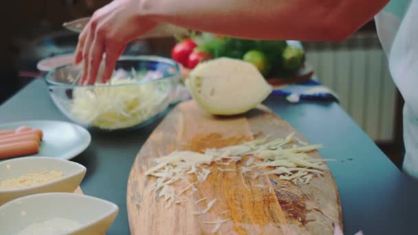 女人把切碎的卷心菜放到一个很深的盘子里 一张桌子的特写 厨房里的烹调 — 图库视频影像