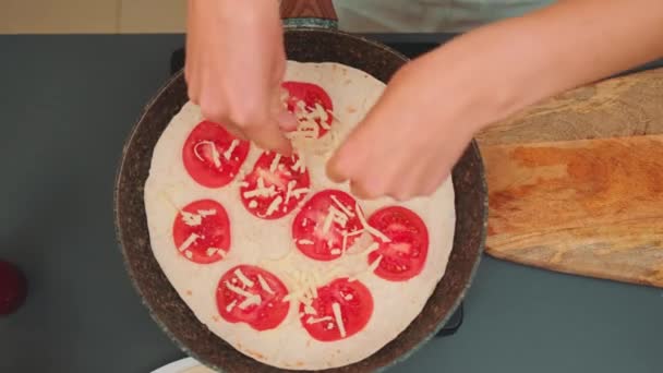 Vrouwenhanden Strooien Geraspte Kaas Bovenop Pitabrood Tomatenringen Bovenaanzicht Keukentafel Koken — Stockvideo