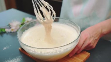 Bir kadın hamuru el çırpmasıyla yener. Lezzetli pasta pişirmek. Masaya yakın çekim. Mutfakta yemek pişirmek.