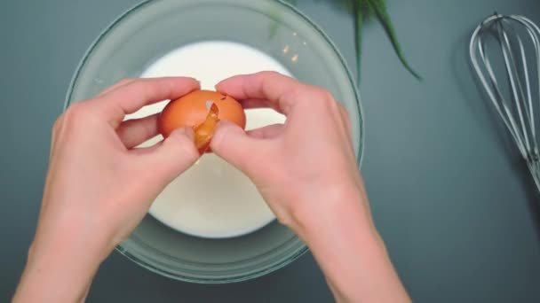 Kvinnliga Händer Bryter Ett Ägg Skål Med Mjölk Ovanifrån Köksbordet — Stockvideo