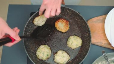 Kadınların elleri, sebze pirzolalarını bir mutfak spatulasıyla lahanadan diğer tarafa çevirir. Mutfak masasının üst manzarası. Mutfakta yemek pişirmek.