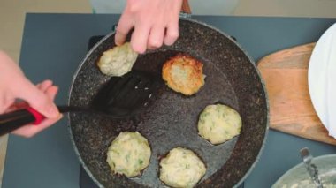 Kadınların elleri, sebze pirzolalarını bir mutfak spatulasıyla lahanadan diğer tarafa çevirir. Mutfak masasının üst manzarası. Mutfakta yemek pişirmek.