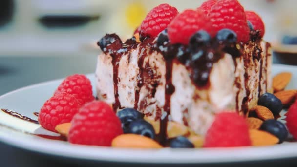一个用浆果和坚果装饰的美味的蛋糕放在盘子里 一张桌子的特写 厨房里的烹调 — 图库视频影像