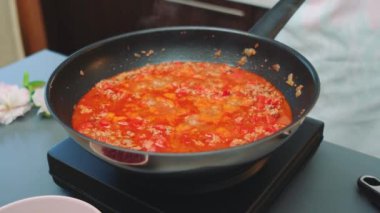 Kadınların elleri kaynar bir tabağı kapakla kaplar. Lezzetli Meksika Chili con Carne. Masanın ortasından. Mutfakta yemek pişirmek.