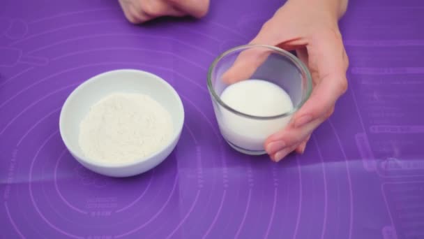 女性の手はコーンスターチに暖かいミルクを注ぐ パンを作るプロセス テーブルの中央ショット キッチンで料理する — ストック動画