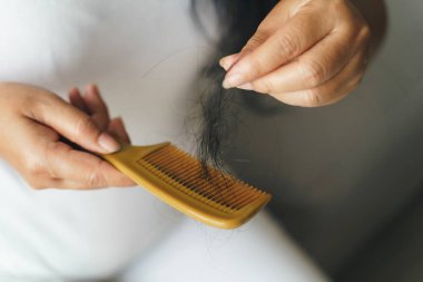 Hair fall problem. Asian woman with comb and hair problem. Hair loss from comb. Hair care and beauty concepts.