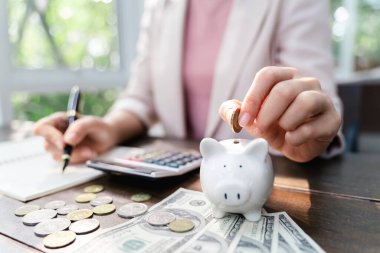 İş kadını eli, tasarruf için kumbaraya para koyuyor. Para ve finansal konsept tasarrufu