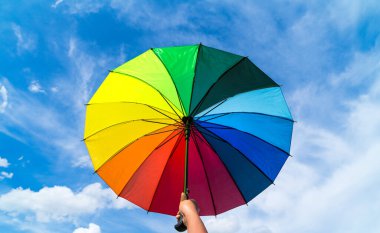 Renkli gökkuşağı şemsiyesi ve mavi gökyüzü arkaplanı. LGBT, Gurur Ayı, Çeşitlilik, Güneş Koruma Konsepti