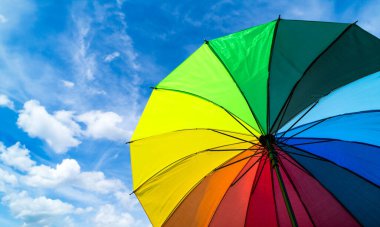Mavi arka planda renkli gökkuşağı şemsiyesi. LGBT, Gurur Ayı, Çeşitlilik, Güneş Koruma Konsepti.