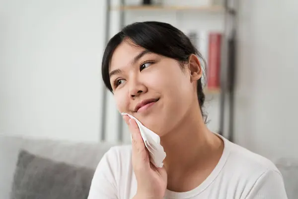 Young Asian woman wiping face with paper towel, Facial Cleansing Wipes, Removing Makeup. Beauty and fashion concept.