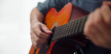 Evdeki oturma odasındaki kanepede oturan akustik gitar çalan adama yakın çekim..