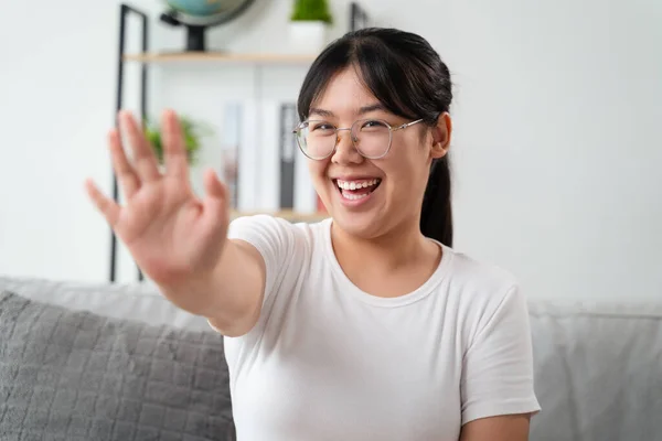 Portrait of young Asian woman wearing eye glasses big smiling and looking at camera with feeling happy and positive in living room at home, meeting, video conference.