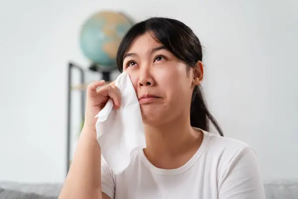 Portrait of a Sad Asian woman crying wipes her tears with a tissue paper towel.